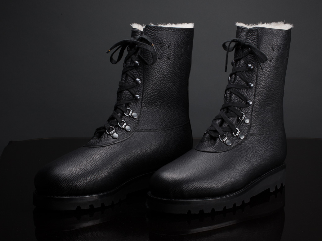 Schwarze Herrenstiefel mit Fellfutter und doppelter Goretex Membran vor dunklem Hintergrund